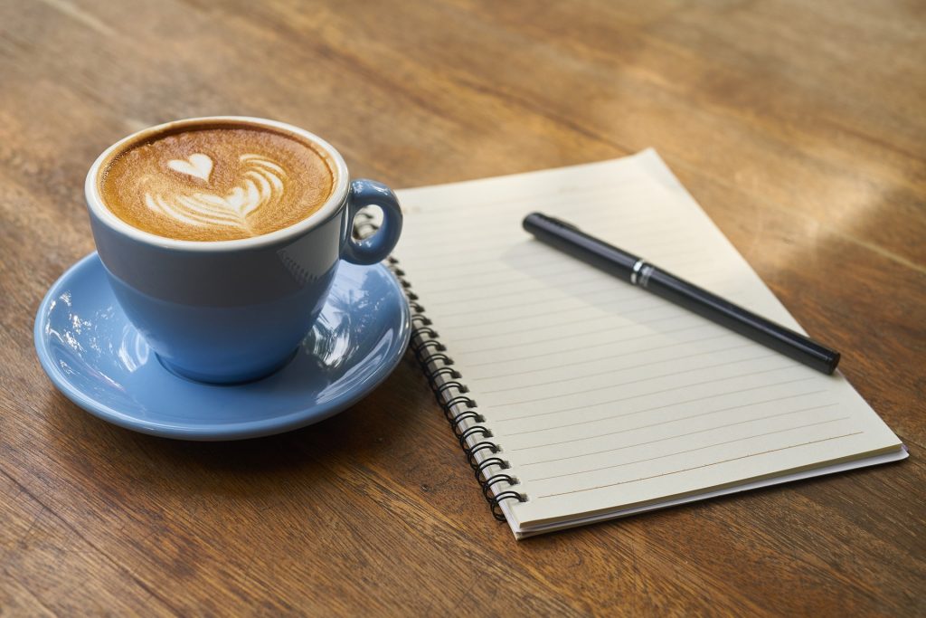 Ambiance écriture manuscrite: Tasse de café bleue, carnet, stylo