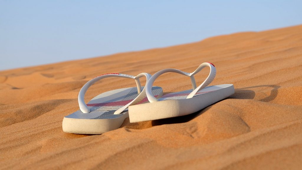 Gérer la canicule en voyage- Iconographie tongs blances sur sable