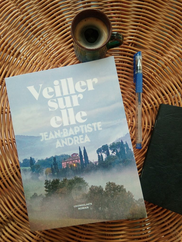 Livre Veiller sur elle, tasse, carnet, stylo sur fond en rotin